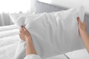 Woman fluffing a small pillow between her hands