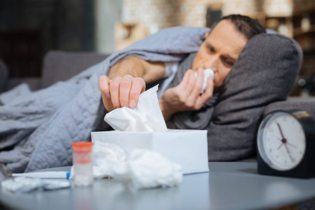 Man blowing nose in bed