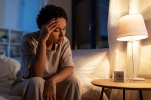 A woman sits on the edge of a bed unable to sleep