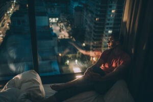 Man sitting in the bedroom with headphones and looking through window