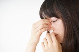 A woman applies tissue to her nose following a nosebleed