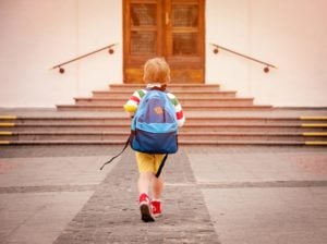 kid walking up to school with bakpack on